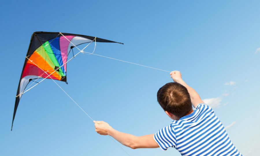 boy flies kite into blue sky